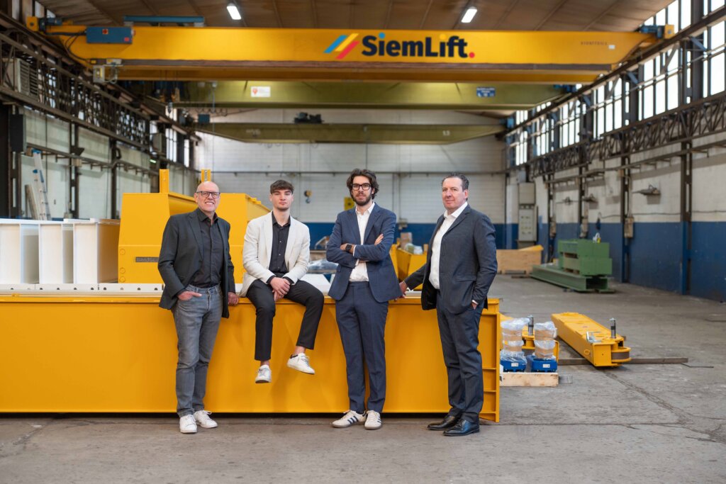 Team Siem Lift in officina con impianti di sollevamento industriale.