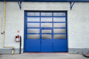 Portone sezionale industriale di colore blu per capannone aziendale, installato da SiemLift.