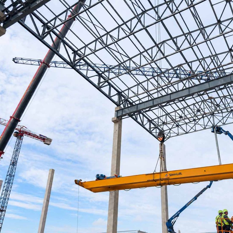 Fase di installazione di una gru a ponte bitrave SiemLift tramite autogru all'interno di un cantiere per un nuovo capannone.