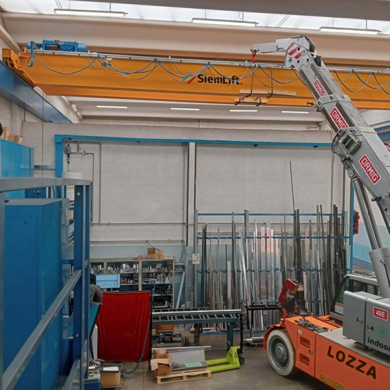 Sistema di sollevamento bitrave giallo installato da SiemLift all'interno di un capannone industriale in Lombardia.